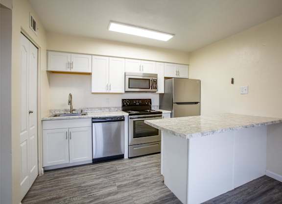 A kitchen with white cabinets and a marble countertop.