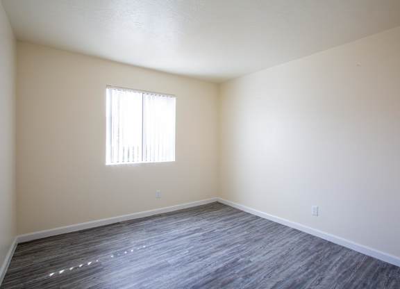 A room with a window and wooden flooring.