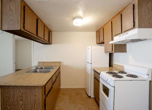 A kitchen with a white stove and wooden cabinets.