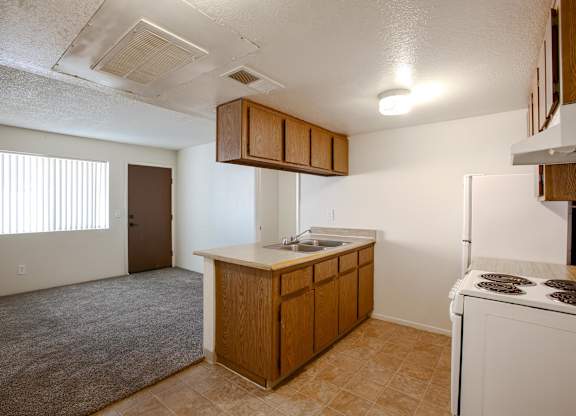 A kitchen with a white stove top oven and a sink.