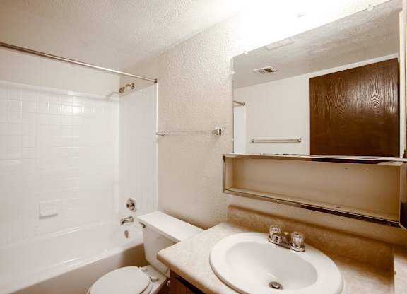 A white bathroom with a toilet, sink, and mirror.