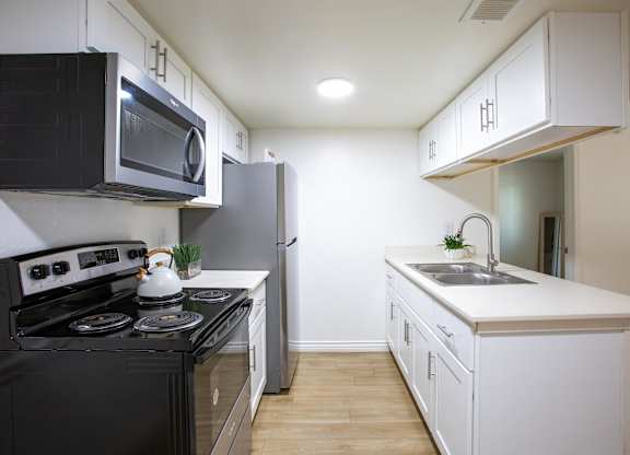 A kitchen with black and white appliances and wooden floors.