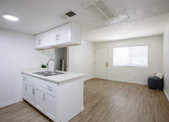 A kitchen with white cabinets and a wooden floor.