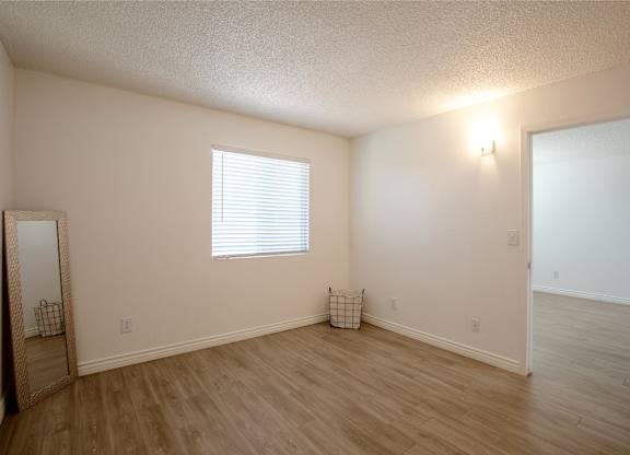 A room with a window and a wooden floor.