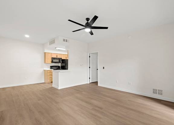 A room with a ceiling fan and a cabinet with a microwave on top.