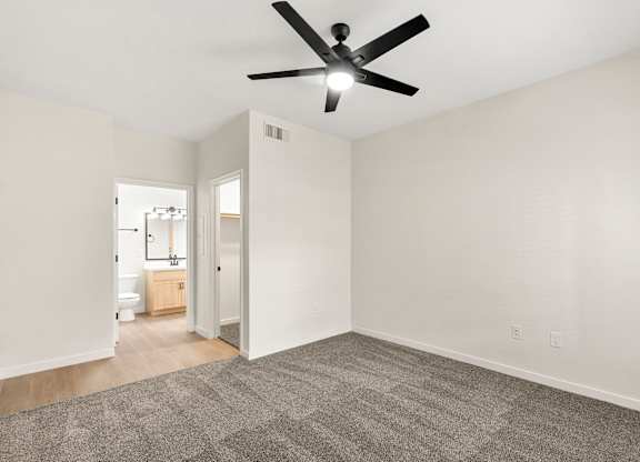 A room with a ceiling fan and carpeted floor.