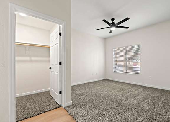 A room with a ceiling fan and a door leading to another room.