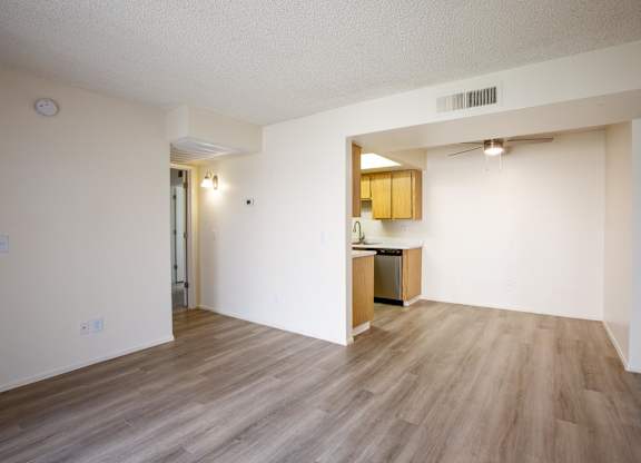 A kitchen area with a sink and cabinets is visible through an open doorway.