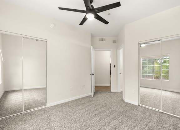 A room with a ceiling fan and carpeted floor.