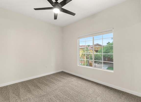 A room with a ceiling fan and a window showing an outdoor view.