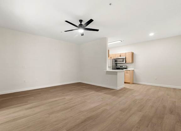 A room with a ceiling fan and a small kitchenette.