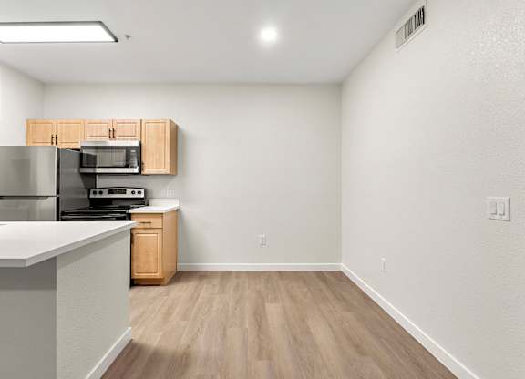 A kitchen with a refrigerator, microwave, oven, and sink.