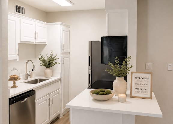 A kitchen with a black fridge and white cabinets.