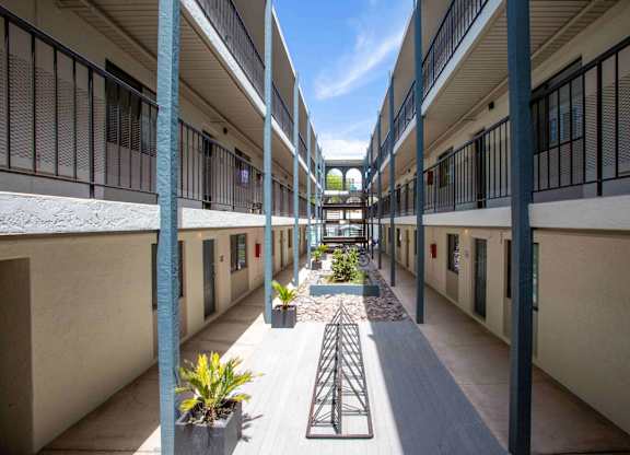 A long courtyard with a bike rack and potted plants.
