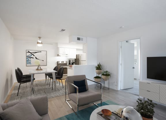 a furnished living room with a dining room table and chairs and a kitchen in the background
