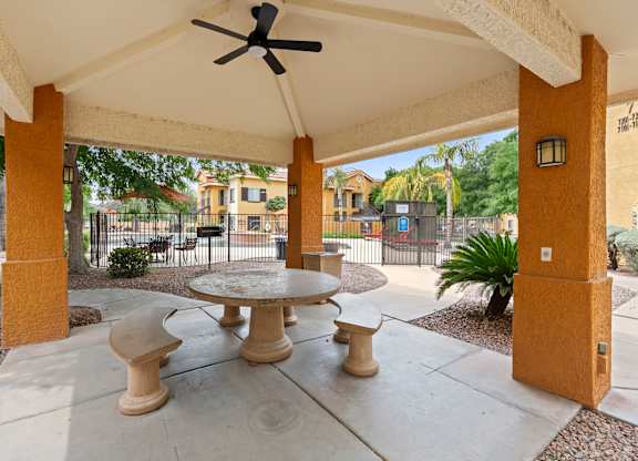 A patio with a table and chairs under a roof.