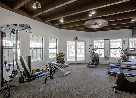 A gym with a variety of equipment including treadmills, weights, and exercise machines.