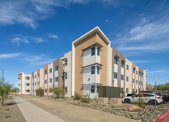 A modern apartment building with a parking lot in front.