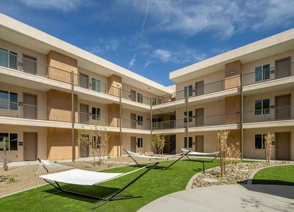 A sunny day at a modern apartment complex with a hammock in the courtyard.