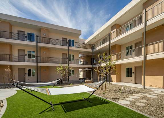 A hammock is strung between two balconies on a sunny day.