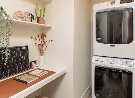 A modern kitchen with a white oven and a wooden shelf.