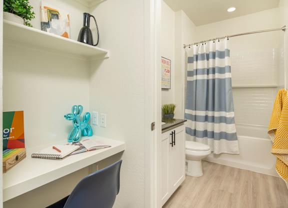 A small bathroom with a white desk and a blue chair.
