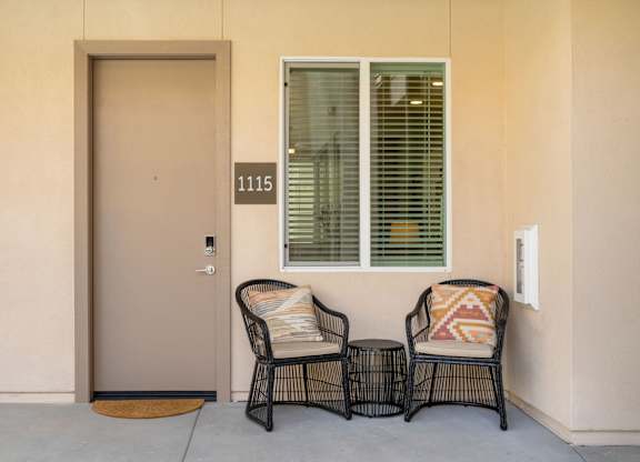 Two chairs with pillows are placed on a patio.