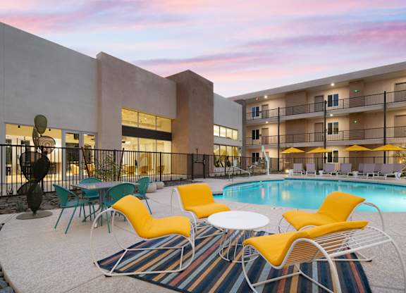 A poolside area with yellow chairs and a white table.