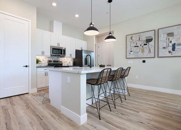 A kitchen with a bar and chairs.