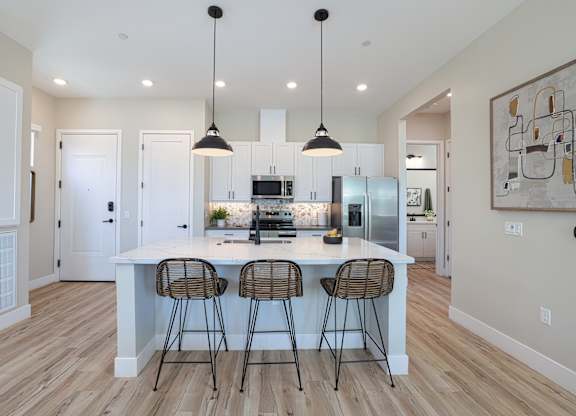 A kitchen with a white island and bar stools.