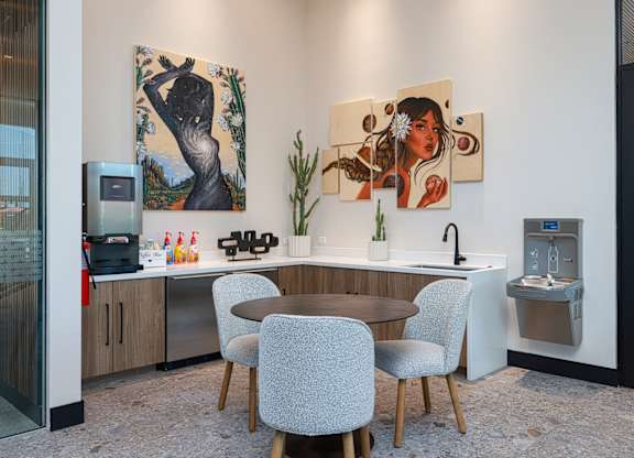 A modern kitchen with a table and chairs and two paintings on the wall.
