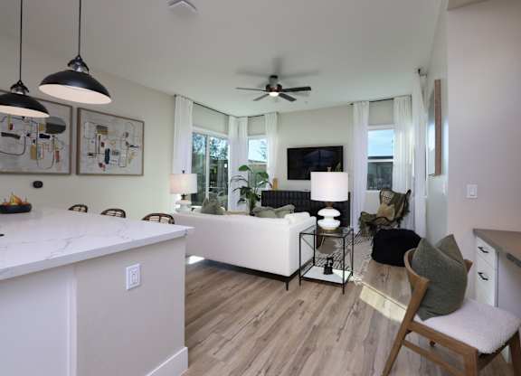 A modern kitchen with a white island and a dining area with a white couch.