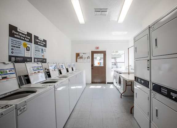 A laundromat with washers and dryers lined up.