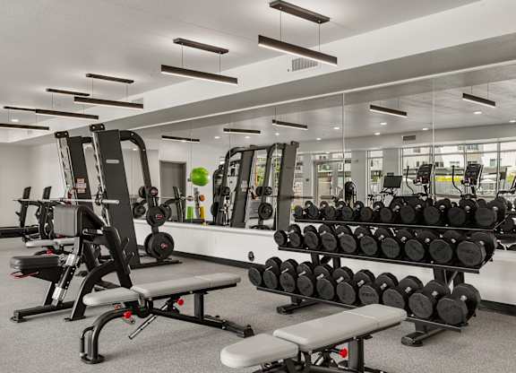 A gym with a variety of equipment including weights and benches.