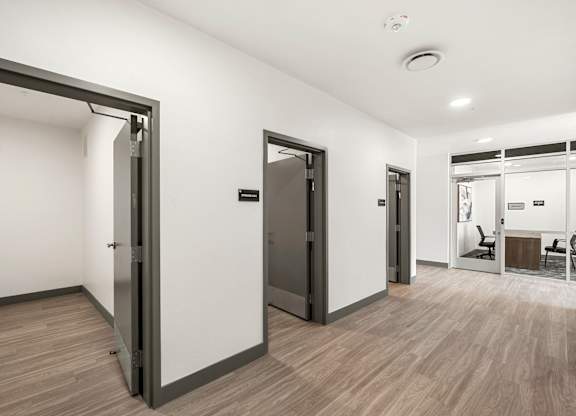 A room with a white wall and a wooden floor with a door.