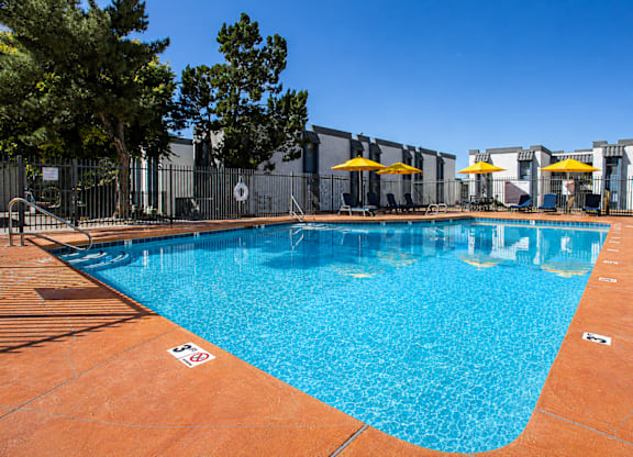A pool surrounded by a fence with a sign on the ground.