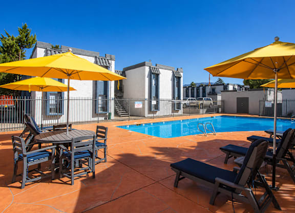 A pool area with sun loungers and umbrellas.