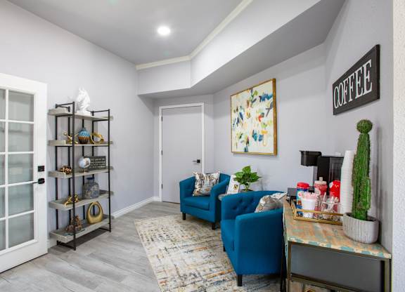 A living room with a blue couch and a coffee sign on the wall.