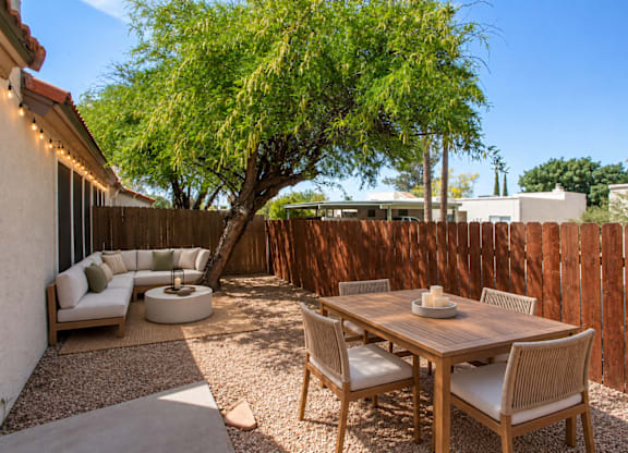 A patio with a table and chairs is surrounded by a wooden fence.