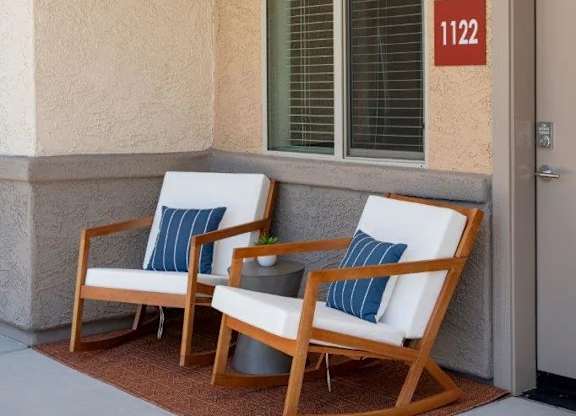 Two chairs are placed on a patio in front of a wall with a number 112 on it.