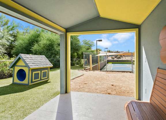 A yellow bench is in the foreground of a picture of a backyard.