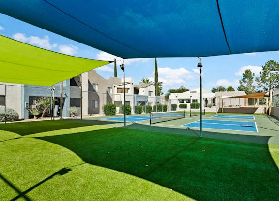 A large green lawn with a blue shade structure over it.