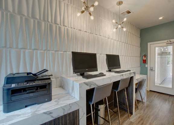 A room with a desk, chairs, and a printer.
