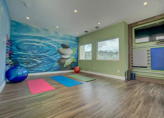 A room with a blue exercise ball and a yoga mat.