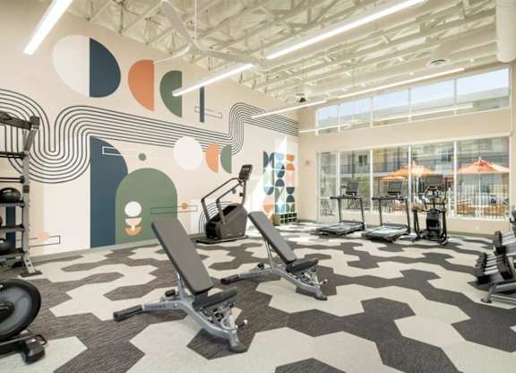 A gym with a variety of equipment including treadmills, weights, and exercise machines.