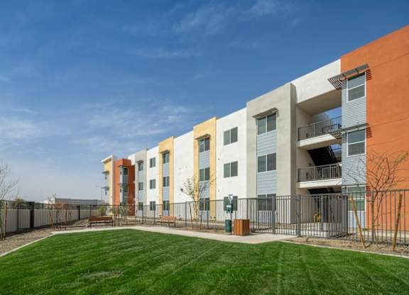 A modern apartment complex with a green lawn in front.