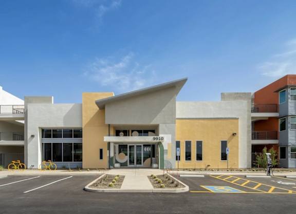 A modern building with a yellow and white facade and a large glass entrance.