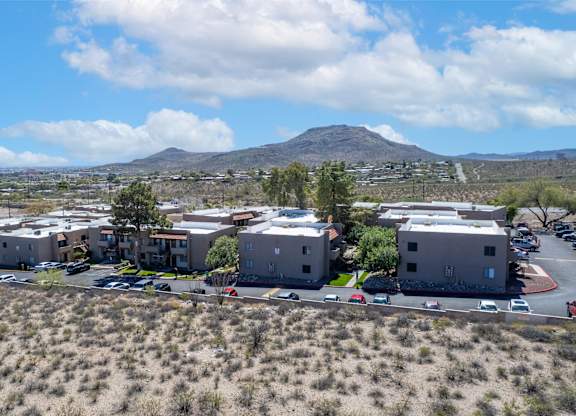 A mountain is in the background of a parking lot with several cars and buildings.