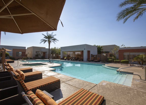 a resort style swimming pool with lounge chairs and umbrellas