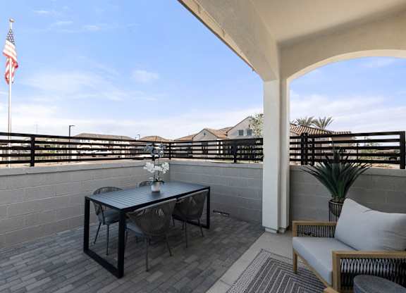 A balcony with a table, chairs, and an American flag.